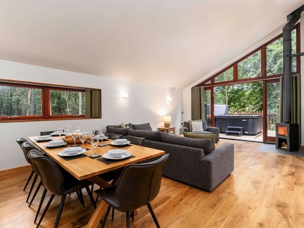 A modern living room with a dining area, large windows, and a fireplace.