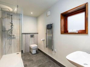 A bathroom with a glass-enclosed shower, a toilet, a towel rack, and a sink.