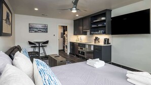 A modern hotel room with a bed, a desk, a kitchenette, and a TV. - 524 Sunsuite (Fripp Island)
