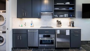 A modern kitchen with dark cabinets, a Bosch oven, a dishwasher, and a coffee maker. - 524 Sunsuite (Fripp Island)