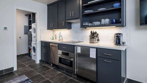 A modern kitchen with dark cabinets, stainless steel appliances, and a built-in dishwasher. - 524 Sunsuite (Fripp Island)