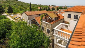 A hillside residential area with terracotta-tiled roofs, stone buildings, and lush greenery. - Heritage Home Cvita (Murter)
