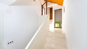 A staircase with white walls and a wooden ceiling, leading to a room with a green curtain. - Heritage Home Cvita (Murter)
