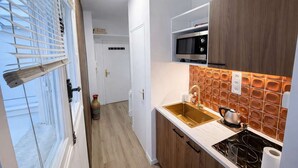 A modern kitchen with a wooden cabinet, a stainless steel microwave, and a tiled backsplash. - Terrace Studio Steps from Trocadéro & Eiffel (Paris)