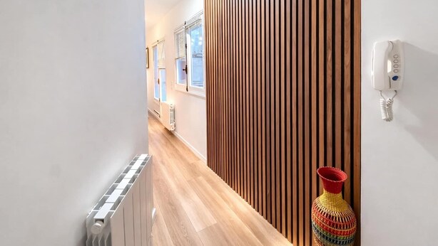A hallway with wooden slats, a radiator, and a colorful vase. - Terrace Studio Steps from Trocadéro & Eiffel (Paris)