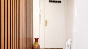 A hallway with a wooden slat wall, a colorful vase, and a white door. - Terrace Studio Steps from Trocadéro & Eiffel (Paris)