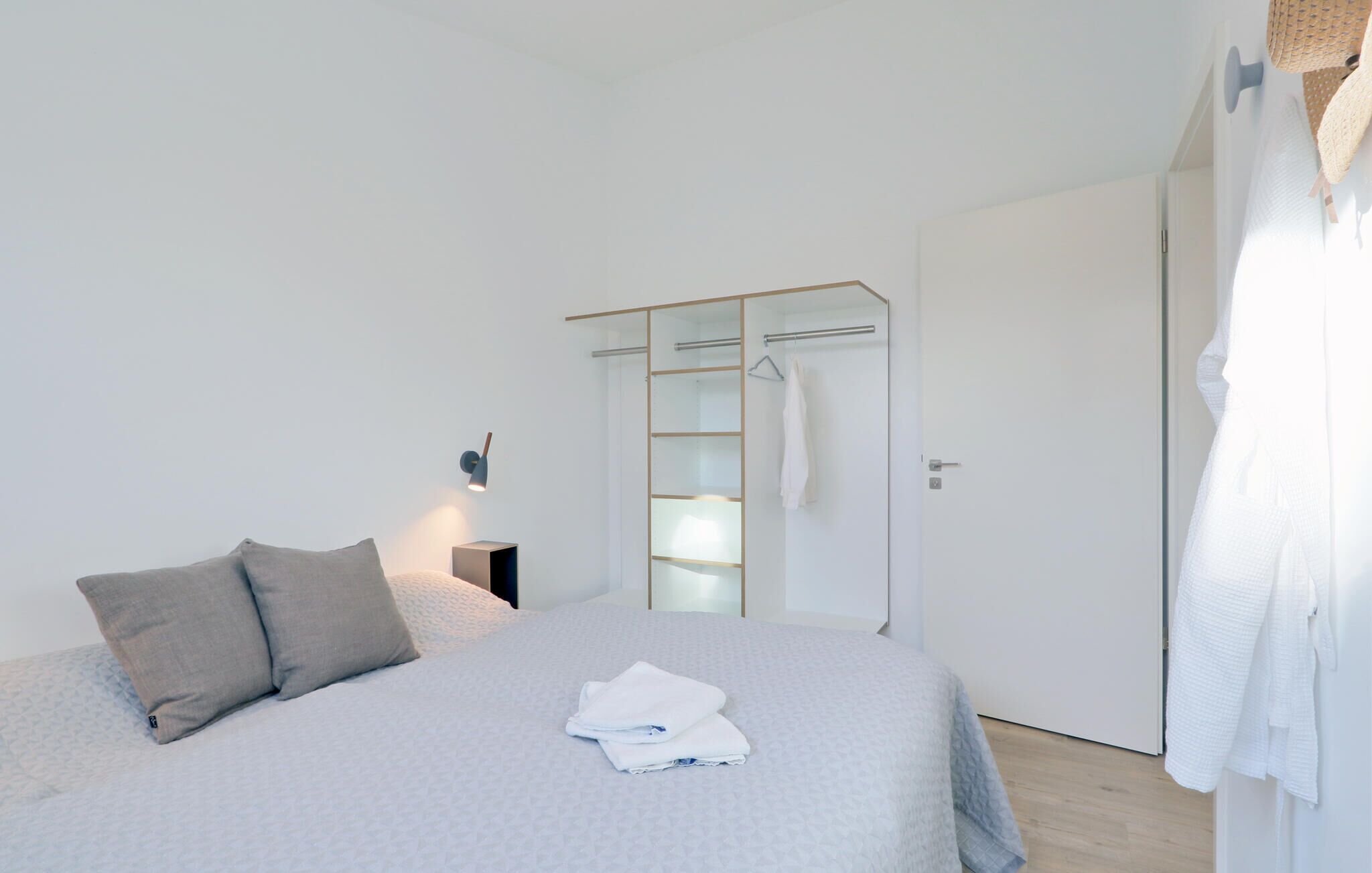 A bedroom with a bed, a bedside table, a wardrobe, and a hanging towel rack.