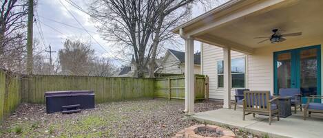 A backyard with a covered patio, outdoor furniture, a fire pit, and a wooden fence.