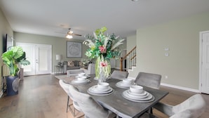 A dining area with a dark wooden table set for six, surrounded by grey upholstered chairs. - Walk to Live Music! Midtown Memphis Home w/ Yard (Memphis)