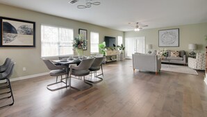 A spacious living room with a dining area, hardwood flooring, and modern decor. - Walk to Live Music! Midtown Memphis Home w/ Yard (Memphis)