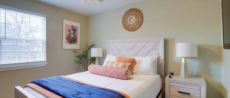 A bedroom with a bed, bedside tables, a ceiling fan, a window, and wall decorations.