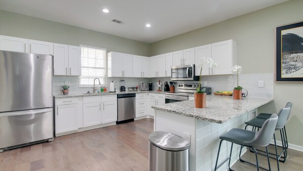 A modern kitchen with white cabinets, stainless steel appliances, and a granite countertop. - Walk to Live Music! Midtown Memphis Home w/ Yard (Memphis)