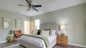 A bedroom with a bed, a ceiling fan, a bedside table with a lamp, and a chair. - Walk to Live Music! Midtown Memphis Home w/ Yard (Memphis)