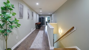 A hallway with a wooden floor, a gray rug, and a staircase with a wooden handrail. - Walk to Live Music! Midtown Memphis Home w/ Yard (Memphis)