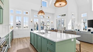 A spacious kitchen with a large island, wooden flooring, and a view of the outside. - Pet-Friendly Coastal Hub w/ Gulf Views, Dual Living Areas & Family Layout (Port Aransas)