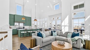 A spacious living area with a large sofa, a coffee table, and a kitchen in the background. - Pet-Friendly Coastal Hub w/ Gulf Views, Dual Living Areas & Family Layout (Port Aransas)