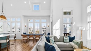 A spacious living area with a large sofa, dining table, and kitchen area. - Pet-Friendly Coastal Hub w/ Gulf Views, Dual Living Areas & Family Layout (Port Aransas)