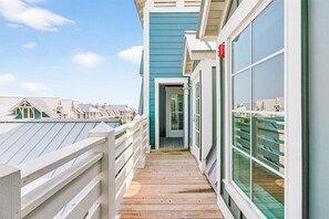 A wooden deck leading to a building with large windows and a door. - Penthouse-Style Retreat with Stunning Gulf & Bay Views @ Cinnamon Shore North (Port Aransas)