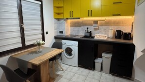 Een kleine keuken met een wasmachine, koffiezetapparaat en broodrooster.