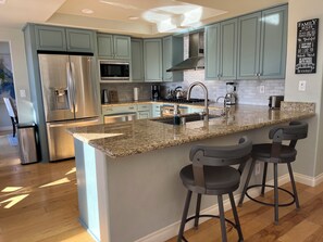 A modern kitchen with teal cabinets, stainless steel appliances, and a granite island with bar stools. - Summerlin Sanctuary! Luxury View Home 4/3 Pool Spa BBQ Pets OK! (Las Vegas)