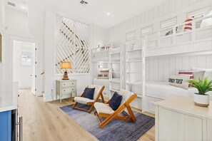 A modern living room with a white color scheme, featuring a sofa set, a wooden coffee table, and a decorative wall unit with storage shelves. - Red White and Saguaro 246 DEW (Port Aransas)