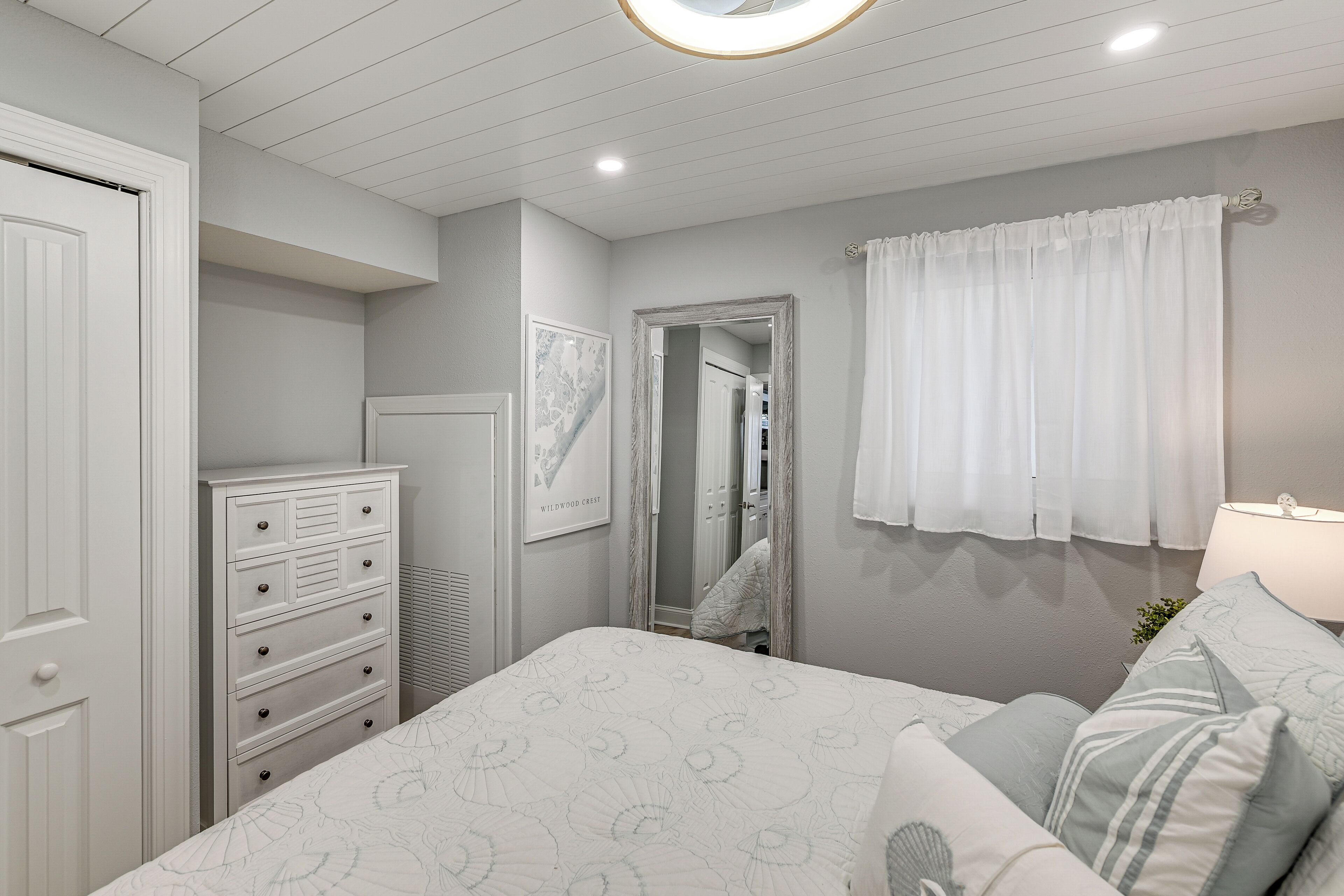 A bedroom with a bed, dresser, and a mirror.