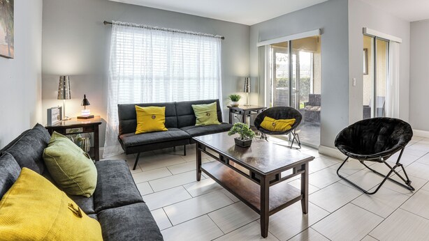A modern living room with a sofa, coffee table, and a black chair. - 5 Mi to Wdw! Spacious Resort Escape w/ Pool Access (Kissimmee)
