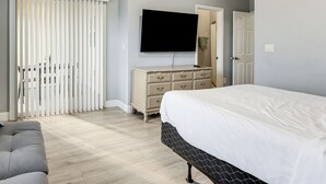 A bedroom with a bed, a dresser, a television, and a sliding door. - 5 Mi to Wdw! Spacious Resort Escape w/ Pool Access (Kissimmee)