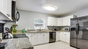 A modern kitchen with white cabinets, stainless steel appliances, and a granite countertop. - 5 Mi to Wdw! Spacious Resort Escape w/ Pool Access (Kissimmee)