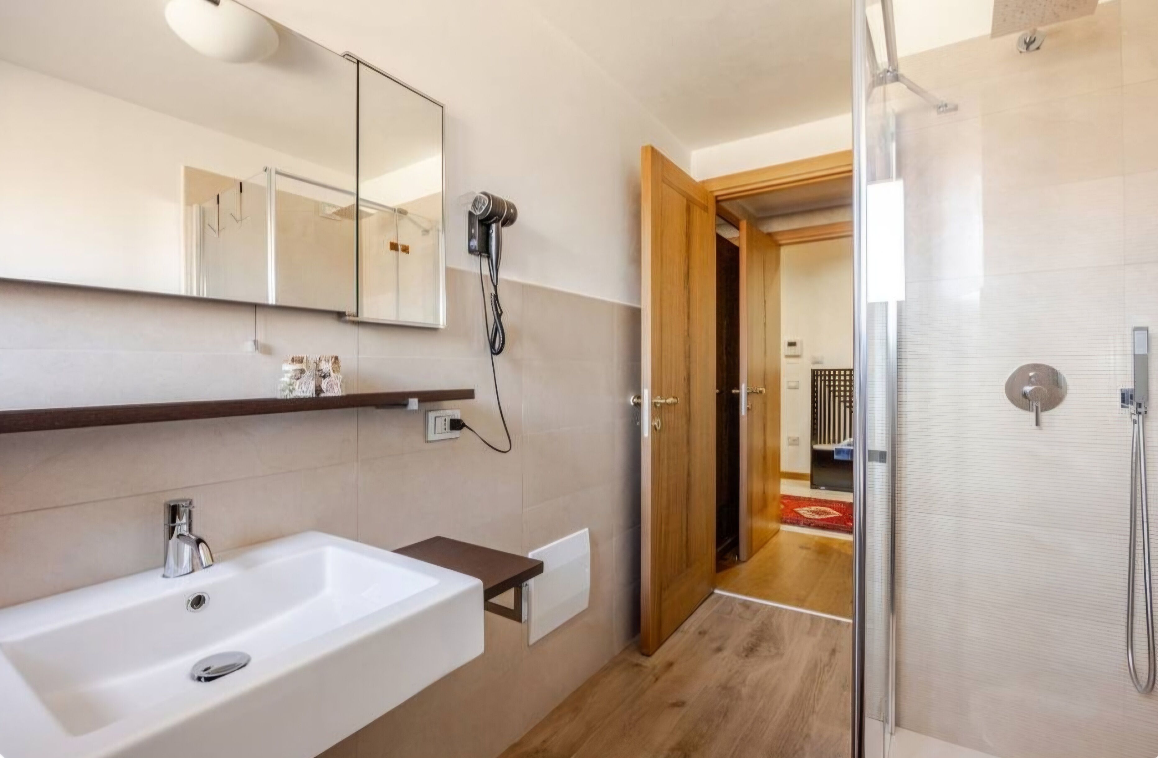 Een moderne badkamer met een grote spiegel, een wastafel, een haardroger en een douche.