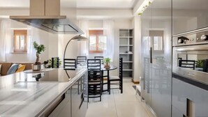 Een moderne keuken met een centraal eiland, inbouwmeubels en een eethoek met een ronde tafel en stoelen.