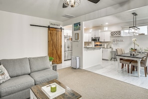 A modern kitchen with white cabinets, a dining area with a table and chairs, and a living room with a sofa and coffee table. - Fenced Yard & Fire Pit! Kennewick Family Retreat (Kennewick)