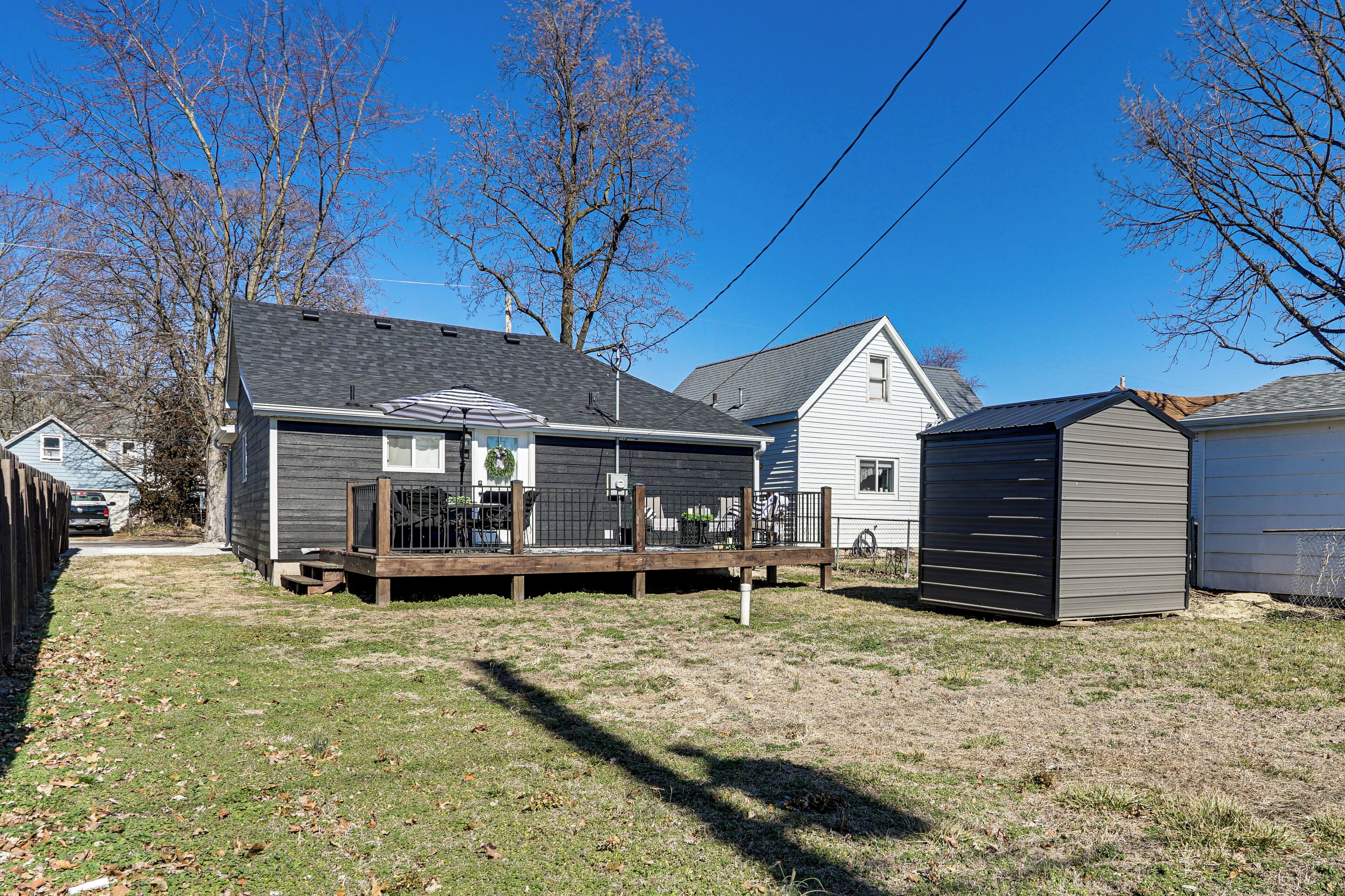 A residential property with a fenced yard, a wooden deck, and a shed.
