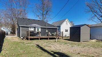 A residential property with a fenced yard, a wooden deck, and a shed.