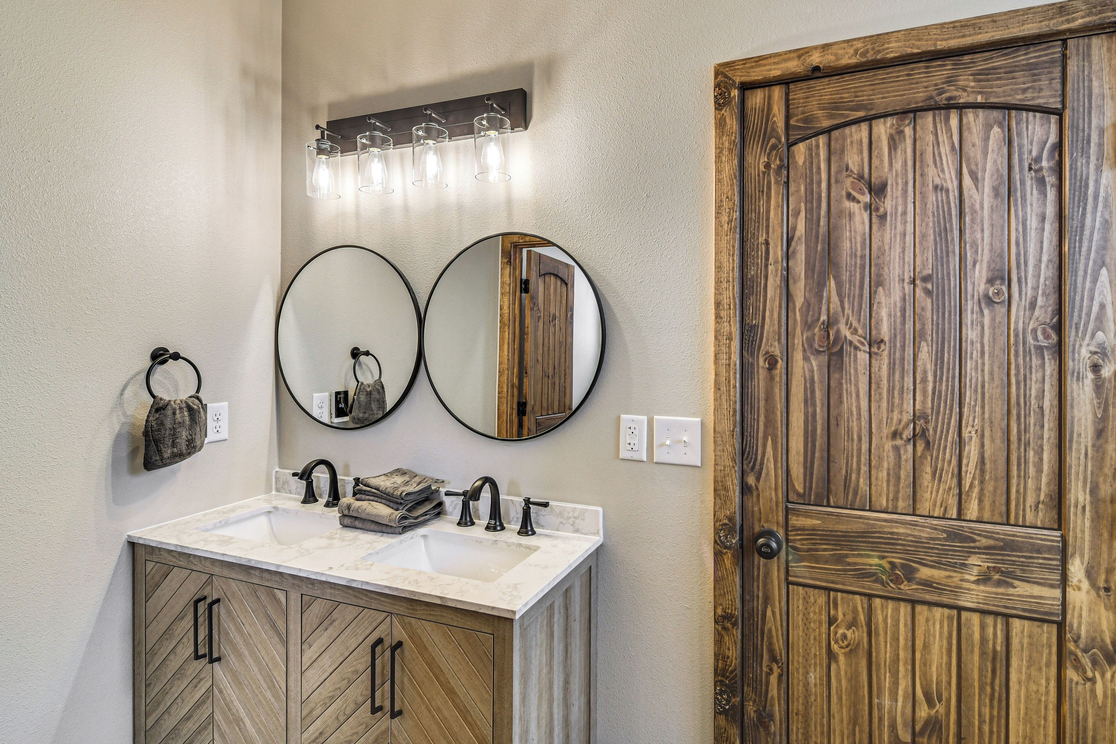 Un baño con puerta de madera, un lavabo con espejo y un perchero para toallas.