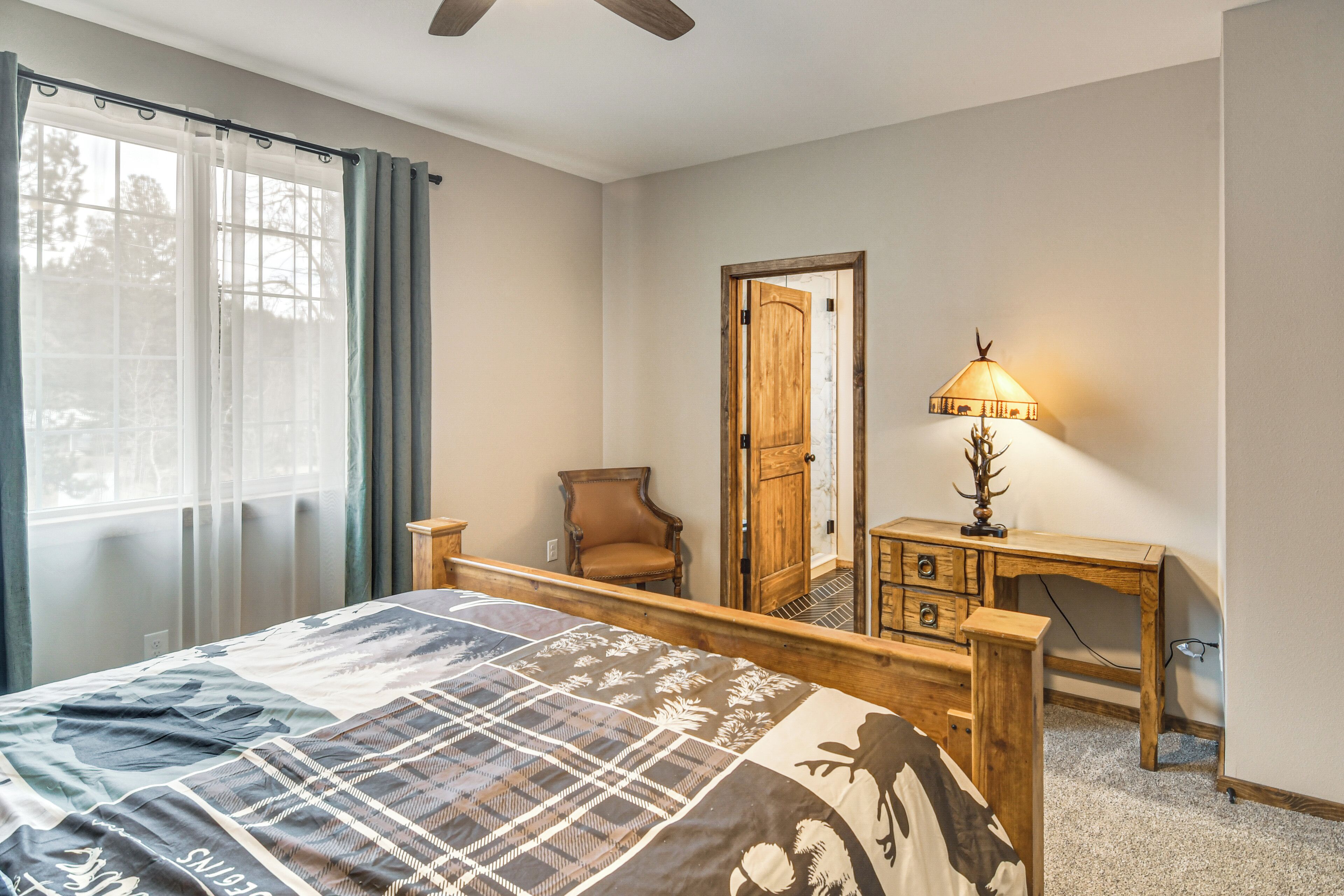 A bedroom with a bed, a wooden nightstand, a chair, and a door.
