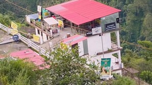 A small, elevated building with a red roof, surrounded by lush greenery. - Sarvaheet (Ukhimath)
