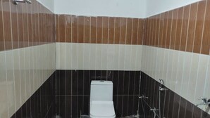 A small bathroom with a toilet, a shower, and a sink. - Sarvaheet (Ukhimath)