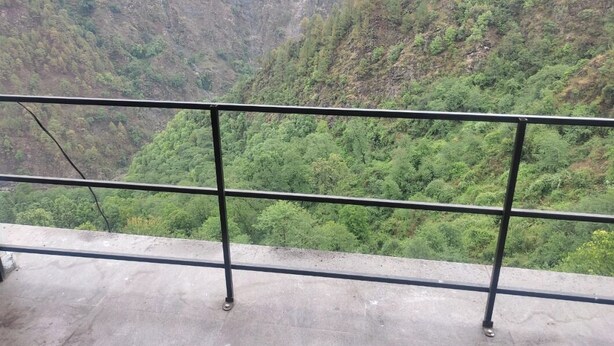 A concrete balcony with metal railings overlooking a lush green valley. - Sarvaheet (Ukhimath)