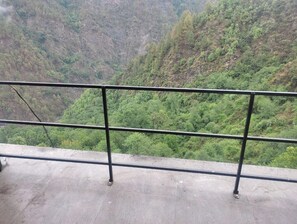 A concrete balcony with metal railings overlooking a lush green valley. - Sarvaheet (Ukhimath)
