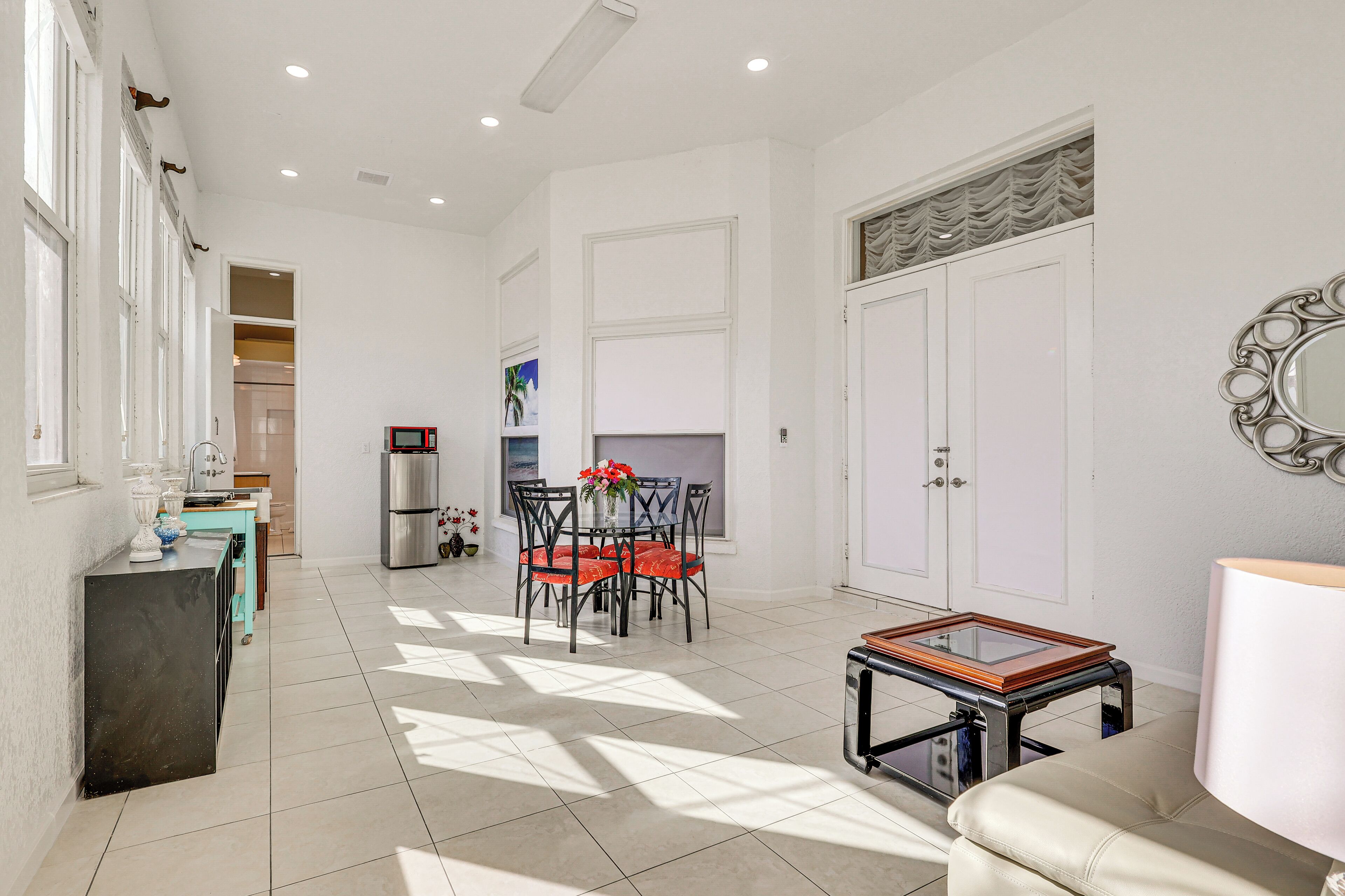 A spacious living area with a dining table, chairs, a sofa, a coffee table, and a kitchen in the background.