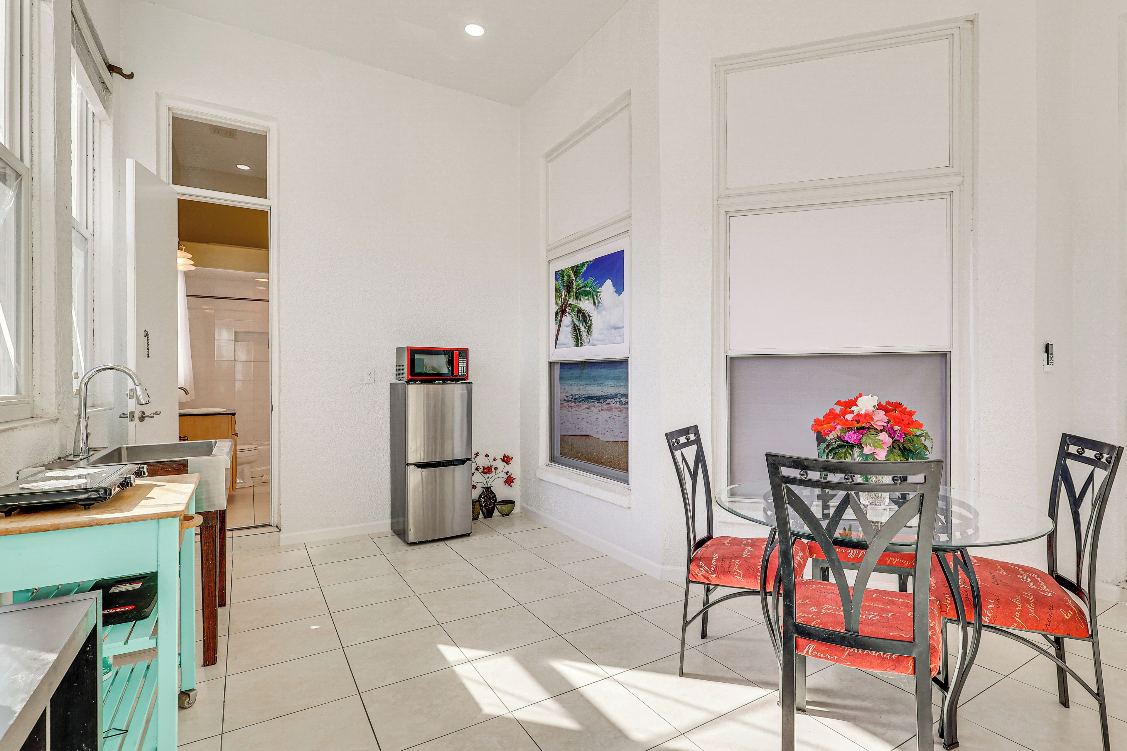 A kitchen with a sink, a refrigerator, and a dining area with chairs and a table.