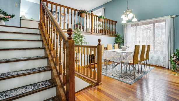 A staircase with wooden railings leading to a second floor, a dining area with a table and chairs, and a chandelier above. - Deck & Outdoor Dining! Spacious St Paul Getaway (Maplewood)