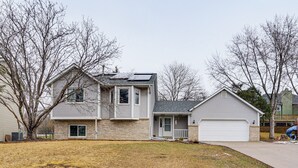 A two-story house with a garage, a covered porch, and a solar panel on the roof. - Deck & Outdoor Dining! Spacious St Paul Getaway (Maplewood)