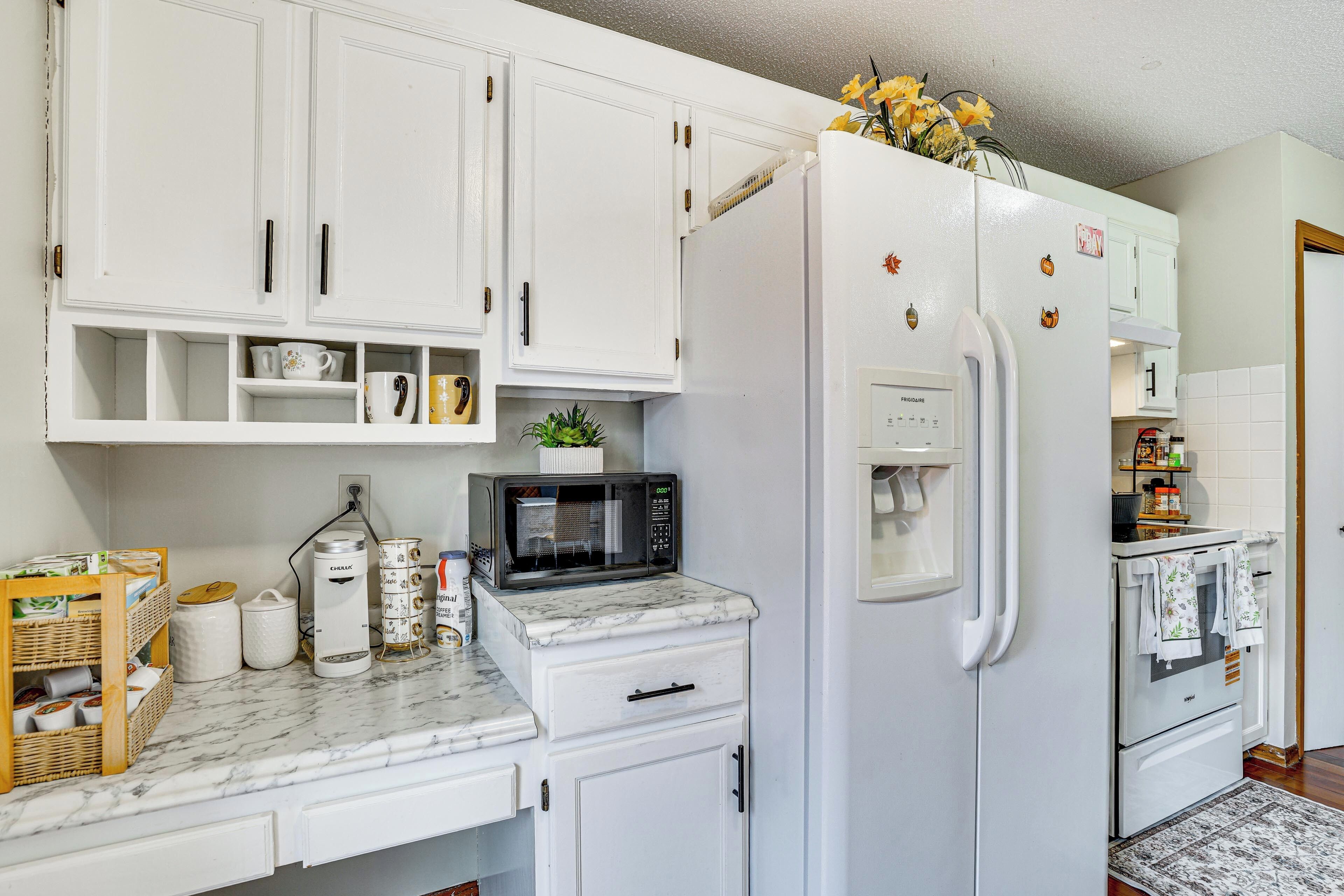 A kitchen with white cabinets, a white refrigerator, a microwave, and a stove.