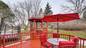 A wooden deck with a gazebo, red chairs, and a table. - Deck & Outdoor Dining! Spacious St Paul Getaway (Maplewood)
