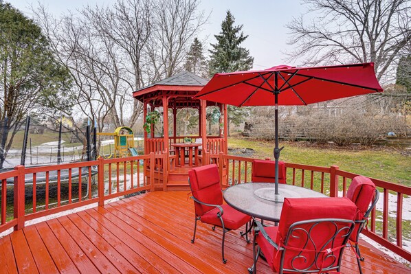A wooden deck with a gazebo, red chairs, and a table. - Deck & Outdoor Dining! Spacious St Paul Getaway (Maplewood)