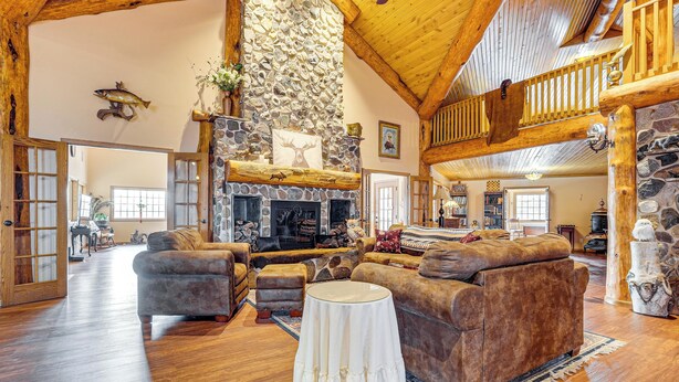 A spacious living room with a stone fireplace, wooden beams, and a cozy seating area.