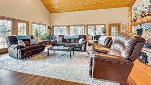 A spacious living room with leather sofas, a coffee table, and a stone fireplace.