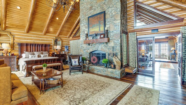A spacious living room with a stone fireplace, wooden ceiling beams, and a large window. - Theater, Gym, Hot Tub: Versailles 'heritage Lodge' (Versailles)